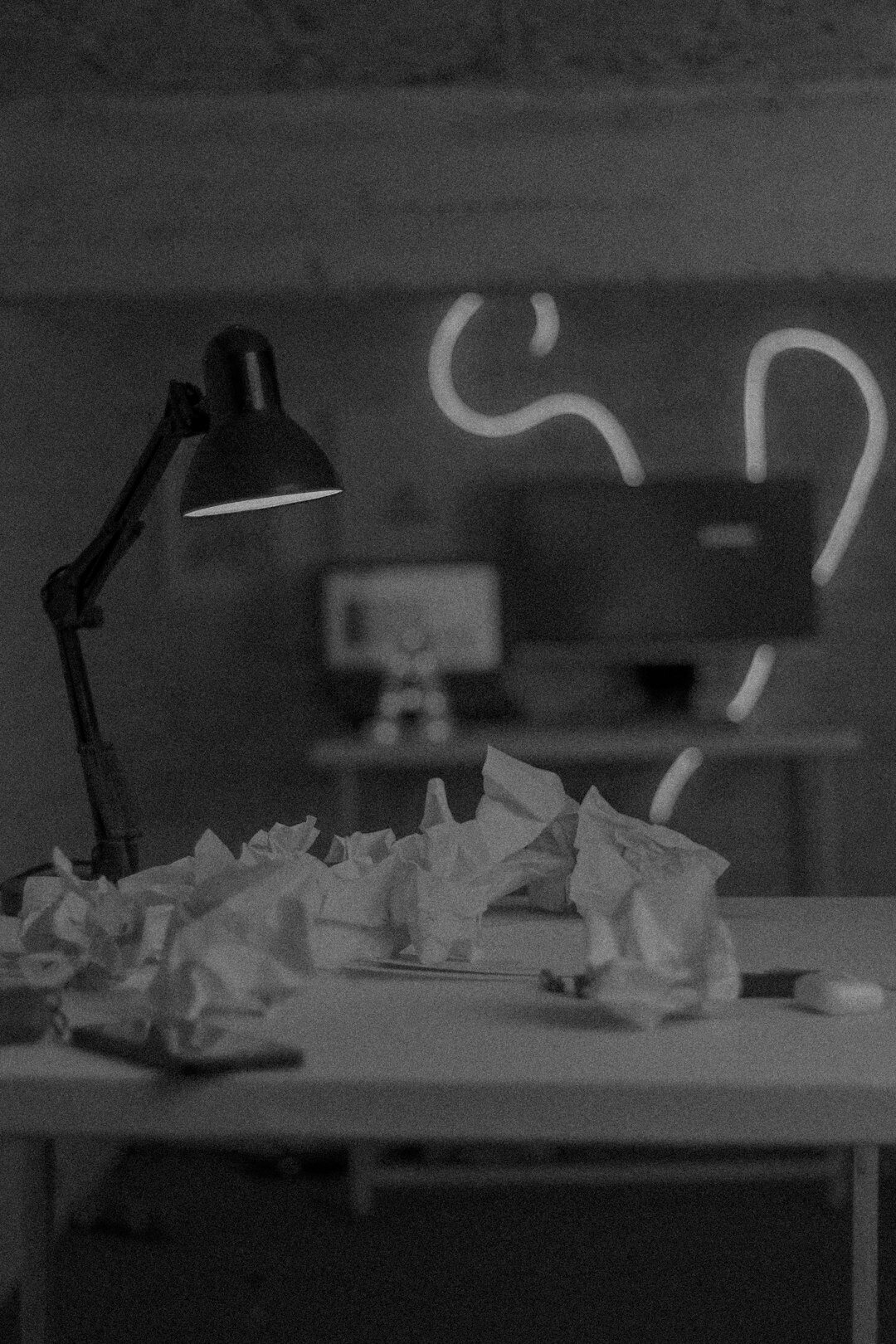 Close-up of a vintage typewriter surrounded by crumpled notes and a coffee cup under warm desk lamp light